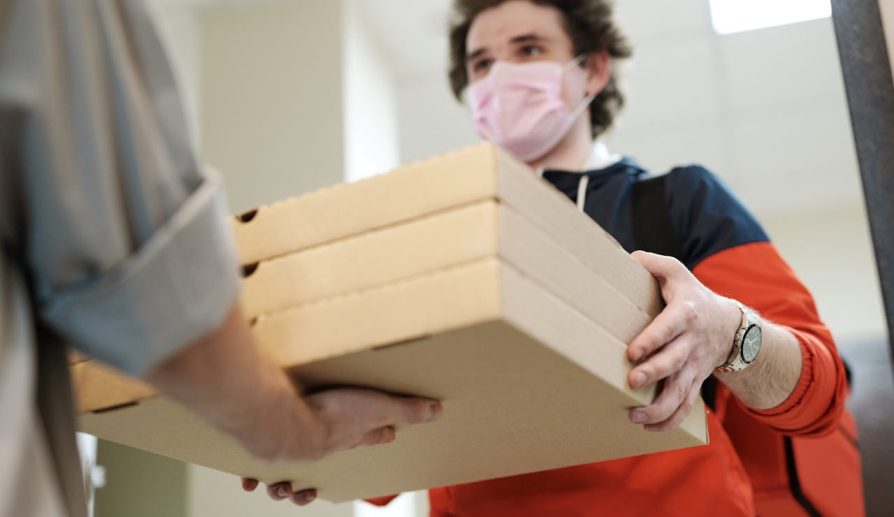 Repartidor de comida entregando cajas de pizza durante las ofertas de Labor Day en Amazon